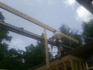Carpenter setting a ridge beam over a new addition frame — Ice Dam Removal by Roofing Brothers in Clanton