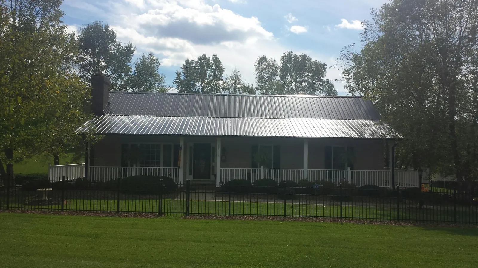 Gray metal roof on a brick ranch with a full width front porch — Gutter Guard Installation work by our crew in Clanton